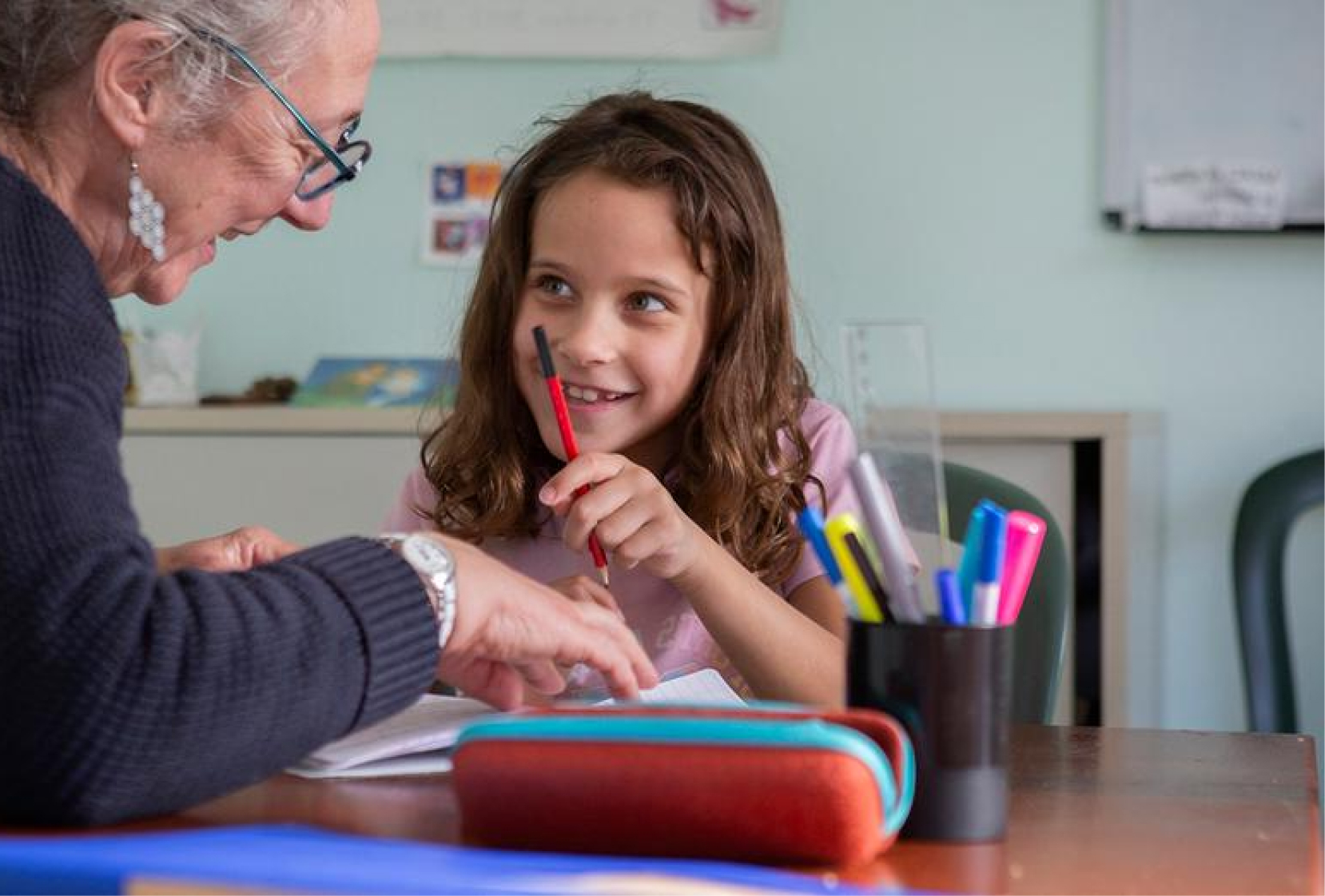 Enfant fille et son assistante maternelle en classe en train de faire des devoirs